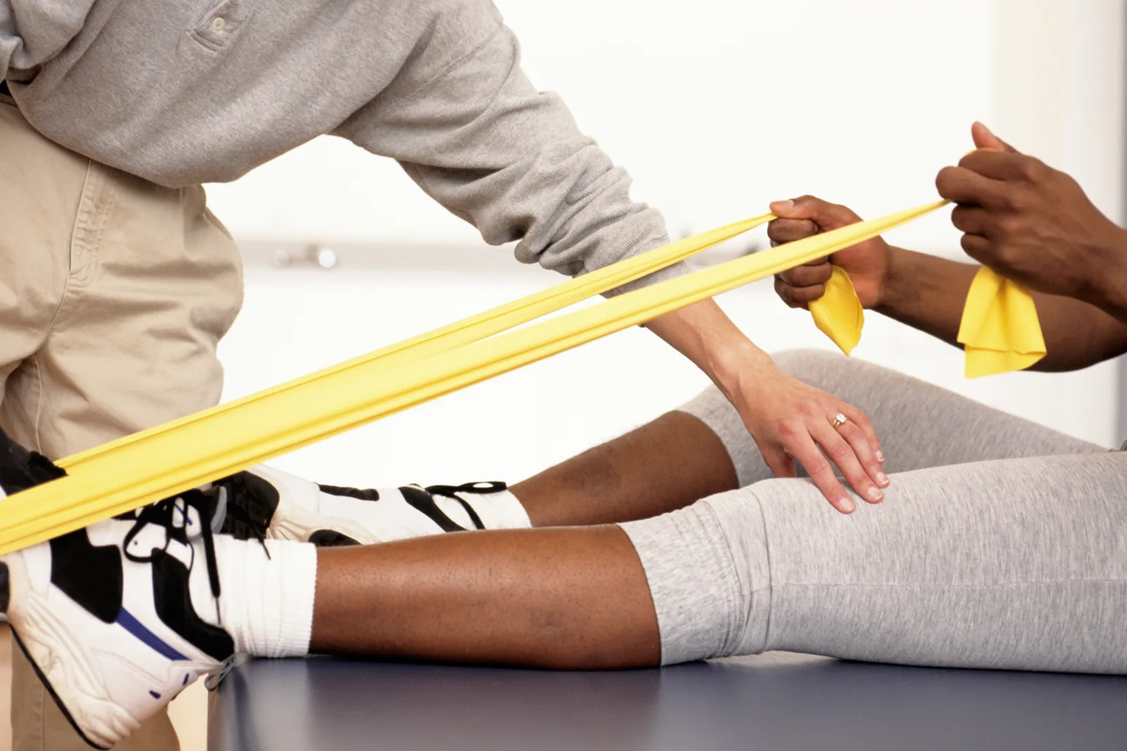 A physical therapist guiding a resistance-band leg exercise